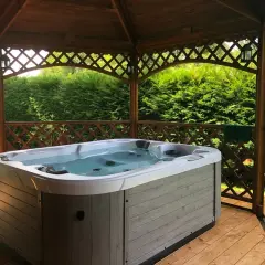 Jacuzzi extérieur prêt pour un entretien relaxant. L'eau claire invite à la détente sous le kiosque en bois.