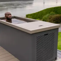 Un homme se baigne dans un spa eau froide extérieur, profitant d'un moment de détente revigorant au bord d'un plan d'eau.