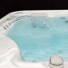 Un jet d'eau forme un arc gracieux au-dessus de l'eau trouble du spa, invitant à la détente.