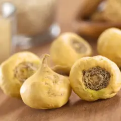 Cinq racines de maca jaunes, entières et séchées, reposent sur une surface en bois.