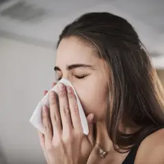 Femme se mouchant avec un mouchoir, possiblement pour soulager une inhalation sinusite.