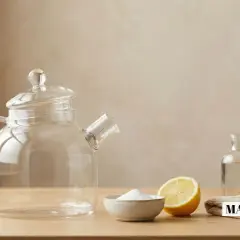 Une théière en verre, du bicarbonate de soude, un citron et une brosse pour nettoyer filtre à thé.