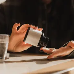 Une personne prend un comprimé de magnésium, prêt à commencer sa cure. Un verre d'eau est à proximité.