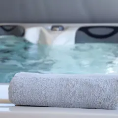 Serviette grise posée sur le bord d'un jacuzzi bouillonnant, parfait pour un spa sportif après l'effort.