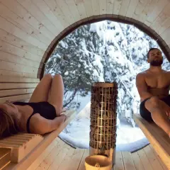 Couple se détendant dans un sauna en bois, avec vue sur une forêt enneigée. Le sauna tous les jours danger, mais ici, c'est un moment de pur bien-être.