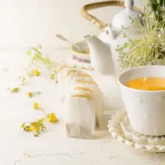 Une tasse de thé ou tisane pour la santé, entourée de fleurs sauvages et de sachets de thé.