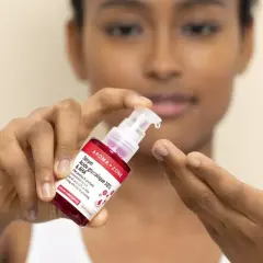 Une goutte de sérum à l'acide glycolique tombe d'une pipette sur le doigt d'une femme.