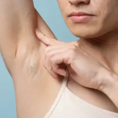 Une personne examine un bouton sous les aisselles, gros plan sur la peau et le doigt.