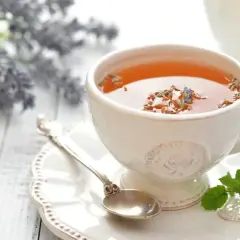 Une tasse de thé à la lavande, parfaite pour savoir quel thé boire le soir. Une cuillère ancienne et des brins de menthe complètent la scène.