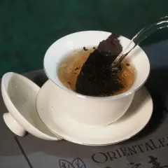 Infusion d'un thé sombre dans une tasse blanche, révélant les fermenté bienfaits. L'eau chaude libère les arômes.