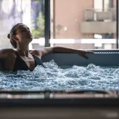 Femme détendue dans un jacuzzi, ignorant les contre-indications possibles. L'eau bouillonnante crée une atmosphère apaisante.