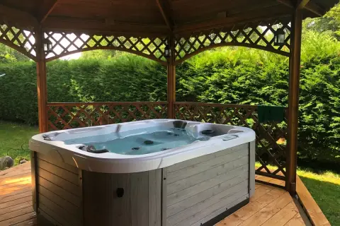 Jacuzzi extérieur prêt pour un entretien relaxant. L'eau claire invite à la détente sous le kiosque en bois.