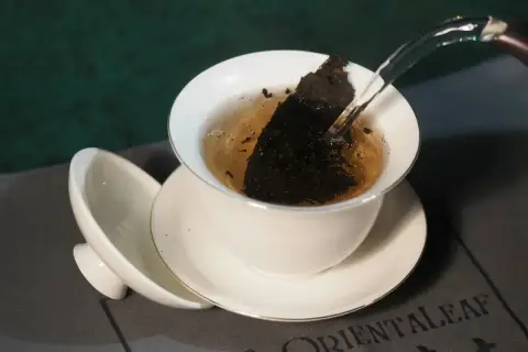 Infusion d'un thé sombre dans une tasse blanche, révélant les fermenté bienfaits. L'eau chaude libère les arômes.