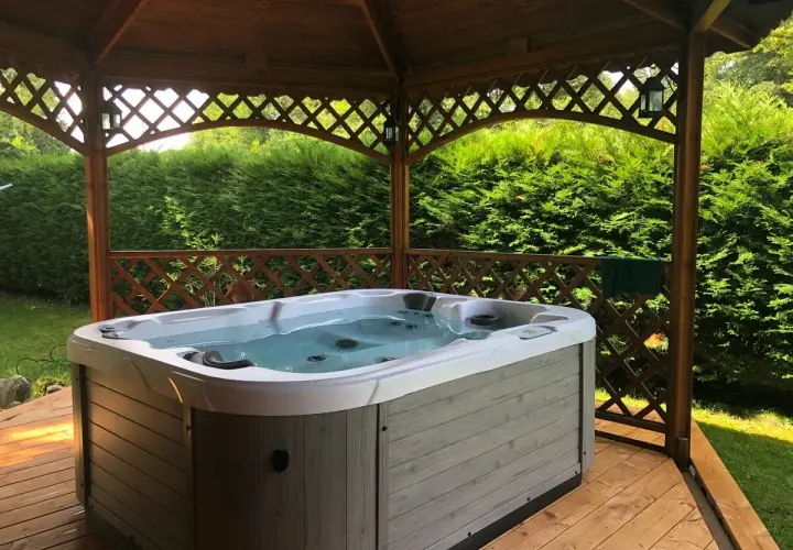 Jacuzzi extérieur prêt pour un entretien relaxant. L'eau claire invite à la détente sous le kiosque en bois.