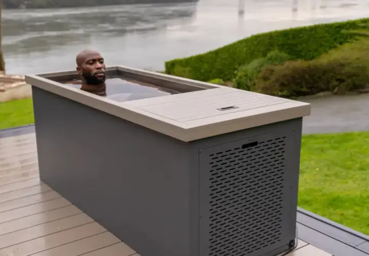 Un homme se baigne dans un spa eau froide extérieur, profitant d'un moment de détente revigorant au bord d'un plan d'eau.
