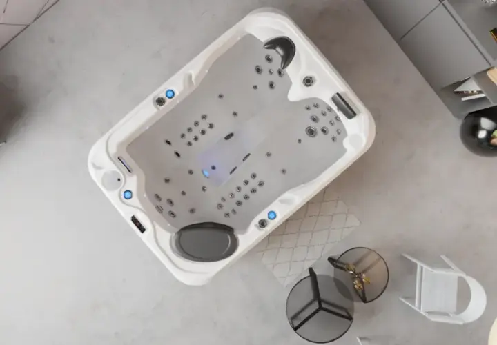 Un spa écologique moderne, avec des jets lumineux, dans un salon épuré. Un canapé gris et une étagère complètent la scène.