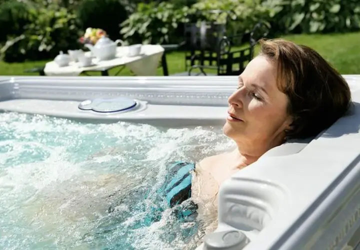 Une femme se détend dans un jacuzzi, profitant de l'eau chaude. Elle se demande combien de temps dans un jacuzzi est idéal pour se relaxer.