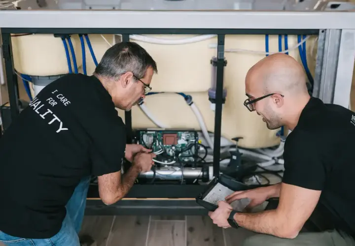 Deux techniciens travaillent sur le système électrique d'un spa, une étape clé pour savoir comment monter un spa.