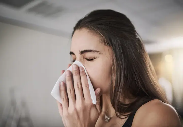 Femme se mouchant avec un mouchoir, possiblement pour soulager une inhalation sinusite.