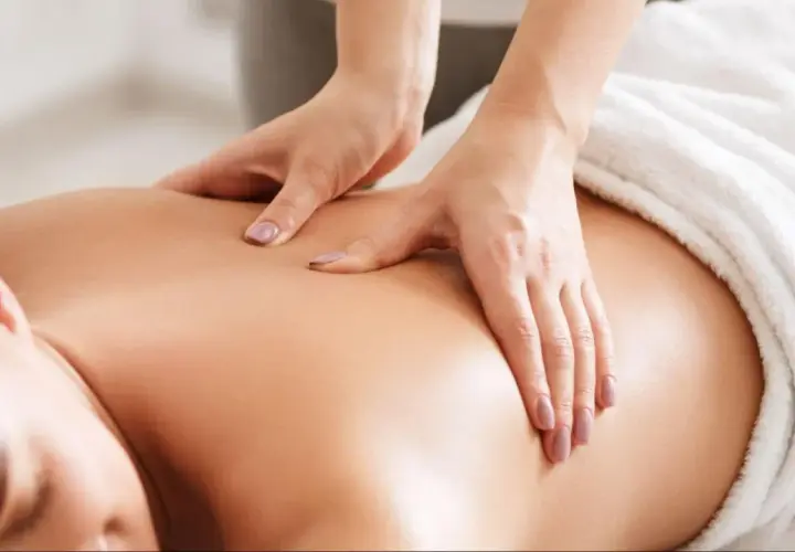 Mains expertes prodiguant un massage relaxant sur le dos d'une personne. Idéal pour savoir que prendre pour aller au spa et se détendre.