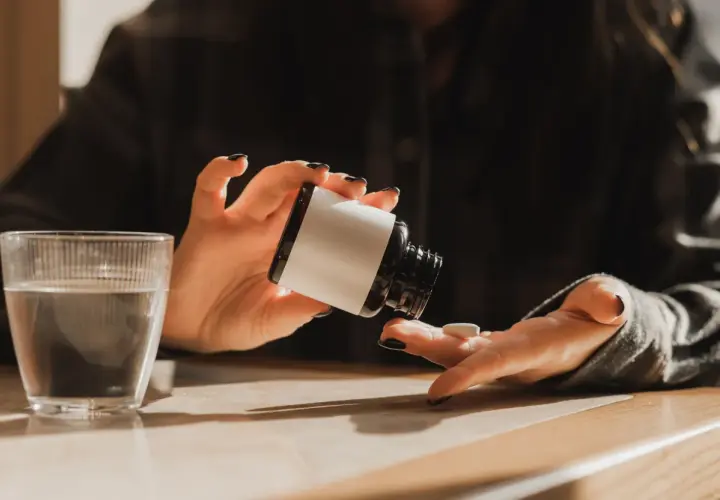 Une personne prend un comprimé de magnésium, prêt à commencer sa cure. Un verre d'eau est à proximité.