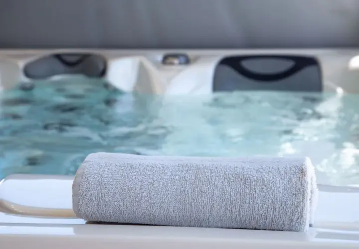 Serviette grise posée sur le bord d'un jacuzzi bouillonnant, parfait pour un spa sportif après l'effort.