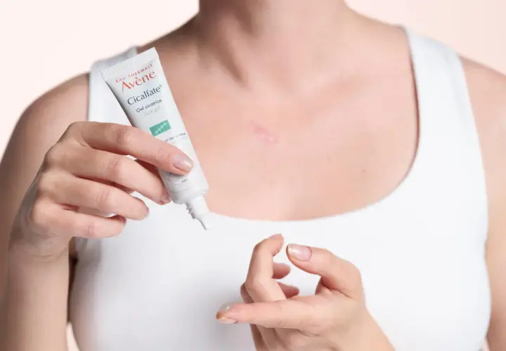 Une femme applique le gel cicatriciel Avène Cicalfate+, la meilleure crème pour cicatrice après opération, sur une légère cicatrice.
