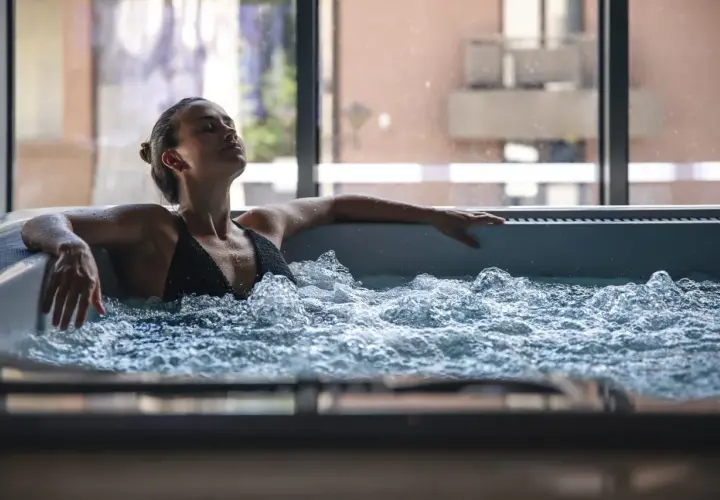 Femme détendue dans un jacuzzi, ignorant les contre-indications possibles. L'eau bouillonnante crée une atmosphère apaisante.