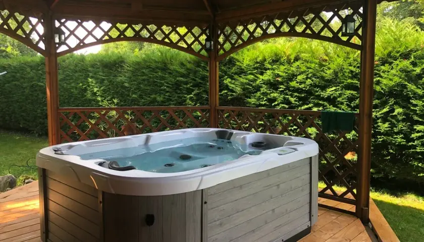 Jacuzzi extérieur prêt pour un entretien relaxant. L'eau claire invite à la détente sous le kiosque en bois.