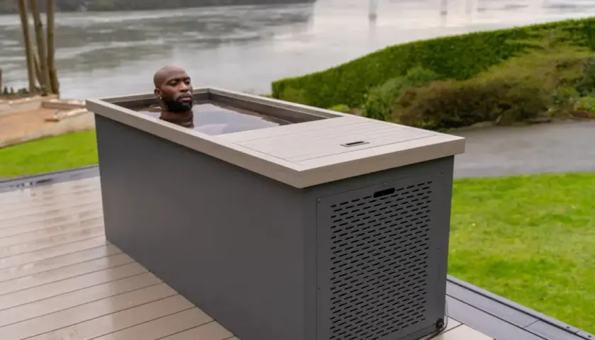 Un homme se baigne dans un spa eau froide extérieur, profitant d'un moment de détente revigorant au bord d'un plan d'eau.