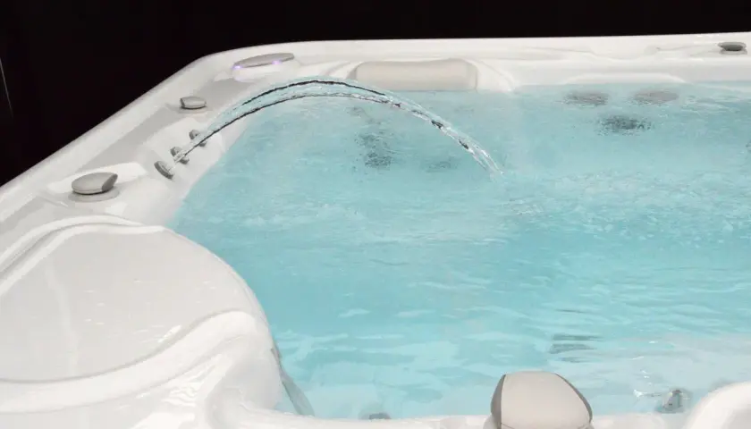 Un jet d'eau forme un arc gracieux au-dessus de l'eau trouble du spa, invitant à la détente.