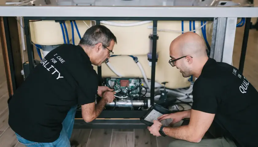 Deux techniciens travaillent sur le système électrique d'un spa, une étape clé pour savoir comment monter un spa.