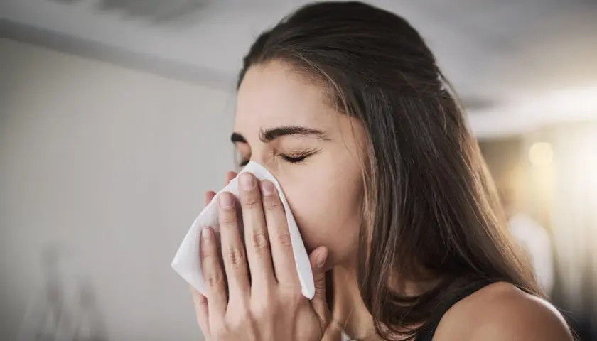 Femme se mouchant avec un mouchoir, possiblement pour soulager une inhalation sinusite.