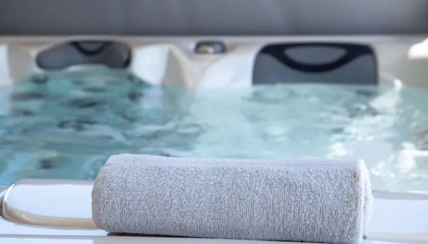 Serviette grise posée sur le bord d'un jacuzzi bouillonnant, parfait pour un spa sportif après l'effort.