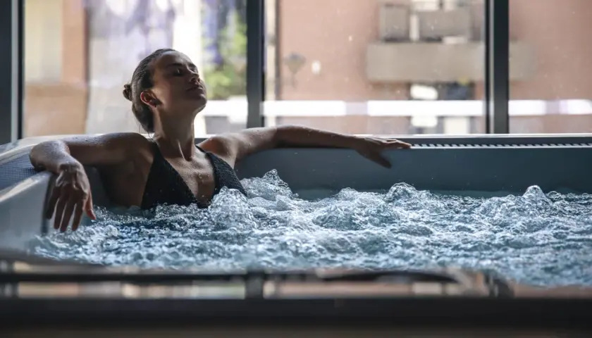 Femme détendue dans un jacuzzi, ignorant les contre-indications possibles. L'eau bouillonnante crée une atmosphère apaisante.