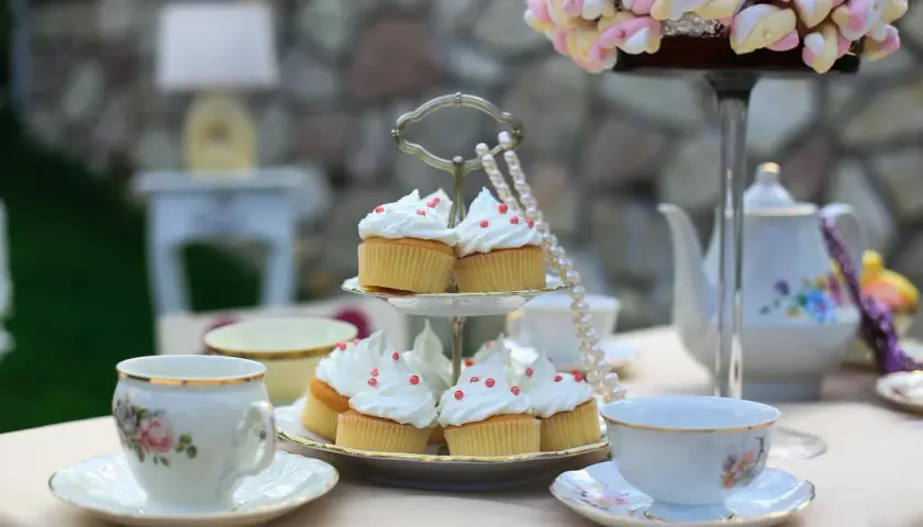 Délicieux cupcakes ornés de crème et de perles rouges, prêts pour un moment de tea time tradition.