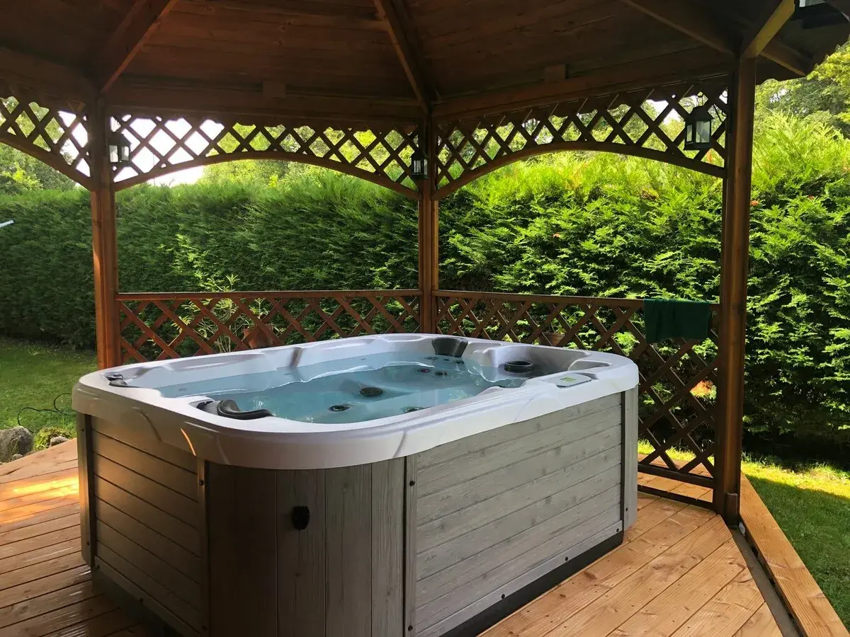 Jacuzzi extérieur prêt pour un entretien relaxant. L'eau claire invite à la détente sous le kiosque en bois.