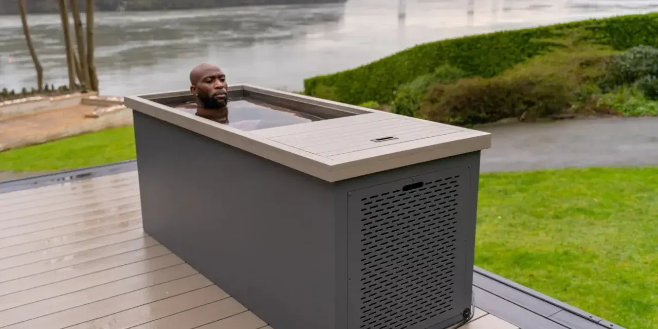 Un homme se baigne dans un spa eau froide extérieur, profitant d'un moment de détente revigorant au bord d'un plan d'eau.