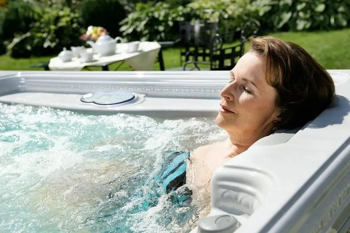 Une femme se détend dans un jacuzzi, profitant de l'eau chaude. Elle se demande combien de temps dans un jacuzzi est idéal pour se relaxer.