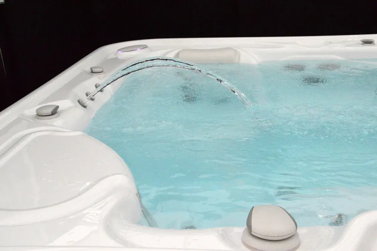 Un jet d'eau forme un arc gracieux au-dessus de l'eau trouble du spa, invitant à la détente.