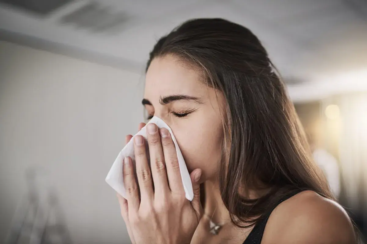Femme se mouchant avec un mouchoir, possiblement pour soulager une inhalation sinusite.