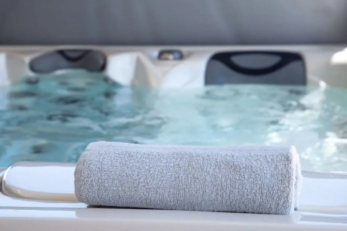 Serviette grise posée sur le bord d'un jacuzzi bouillonnant, parfait pour un spa sportif après l'effort.
