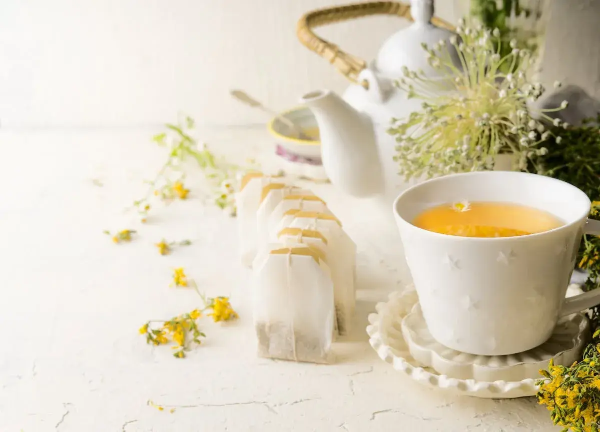 Une tasse de thé ou tisane pour la santé, entourée de fleurs sauvages et de sachets de thé.