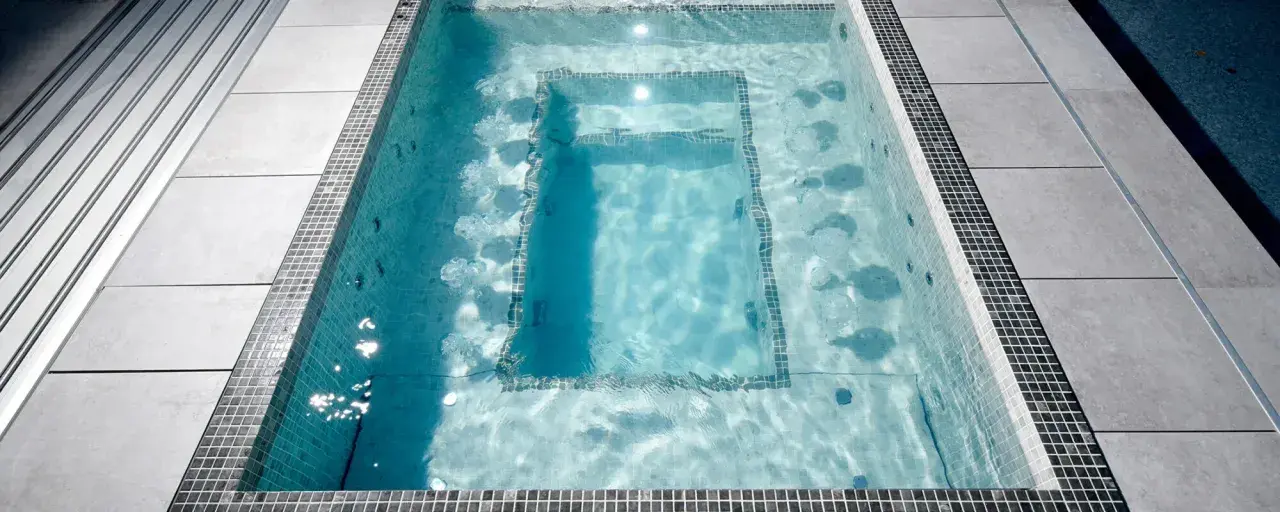 Un jacuzzi moderne avec des jets d'eau, entouré de carrelage et de dalles grises. Le poids d'un jacuzzi rempli d'eau est considérable.