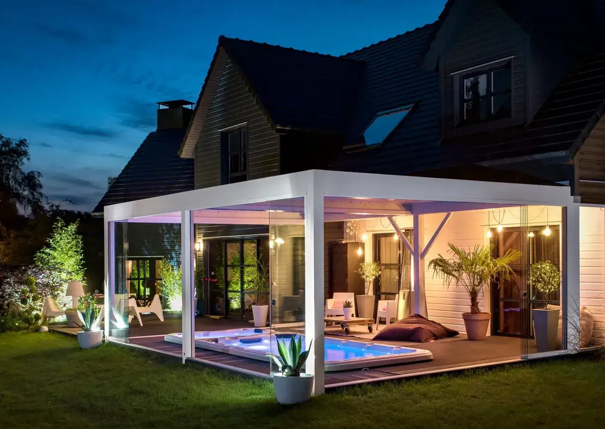 Un luxueux spa sous pergola, illumin&eacute; par des lumi&egrave;res d'ambiance, invite &agrave; la d&eacute;tente dans un jardin paisible.