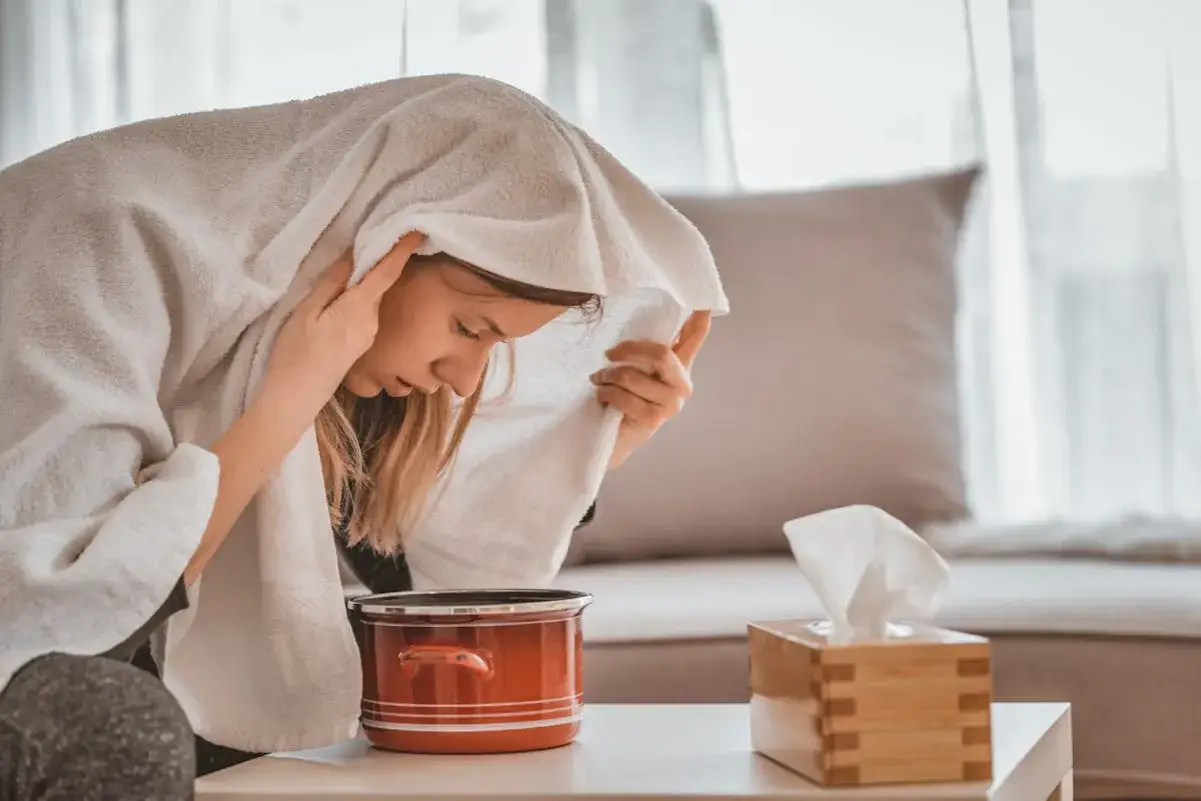 Jeune femme enroulée dans une serviette, profitant d'une inhalation de vapeur de thym pour soulager ses voies respiratoires.
