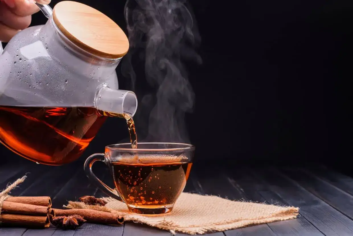 Un th&eacute; noir fumant est vers&eacute; dans une tasse, invitant &agrave; la d&eacute;tente et au sommeil. Cannelle et anis &eacute;toil&eacute; compl&egrave;tent cette sc&egrave;ne apaisante.