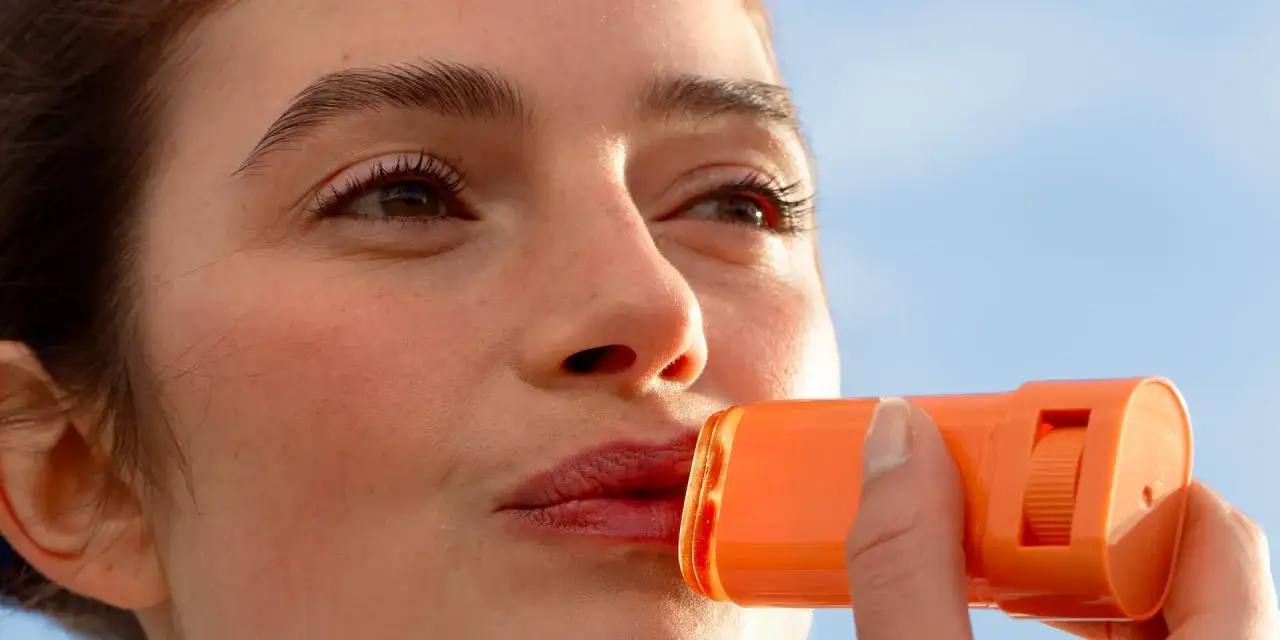 Une femme applique un baume protecteur sur ses lèvres pour éviter le coup de soleil.