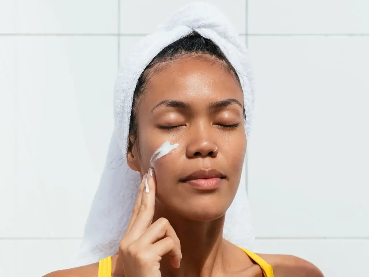 Une femme applique de la cr&egrave;me sur son visage, un geste simple pour savoir comment hydrater sa peau.
