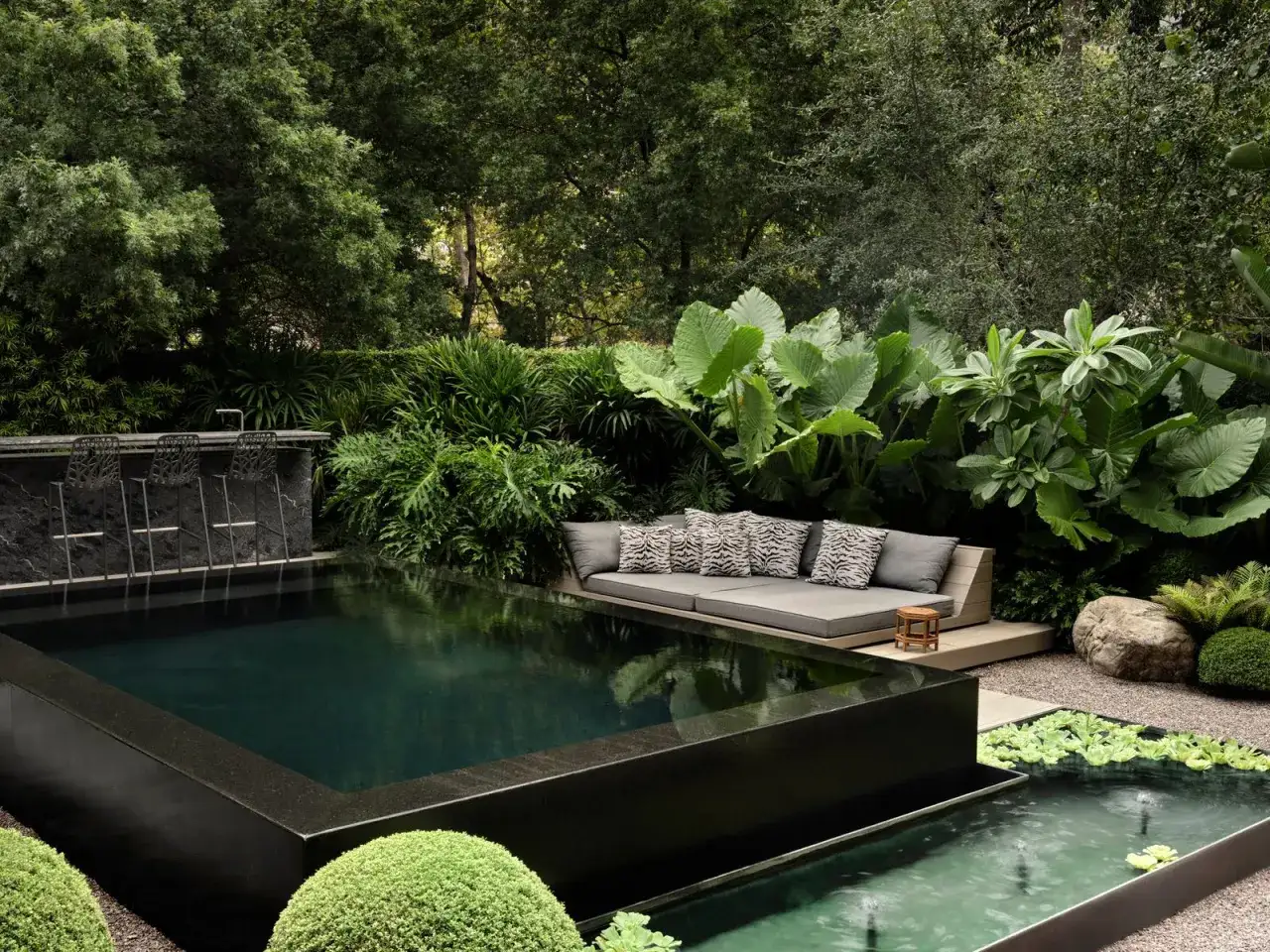Un espace extérieur luxuriant avec une piscine sombre, un bar et un canapé invitant. Le bienfait jacuzzi est palpable dans cette oasis de détente.
